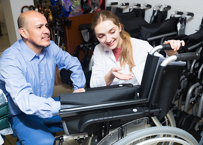 Man and woman crouched down looking at a standard wheelchair together.